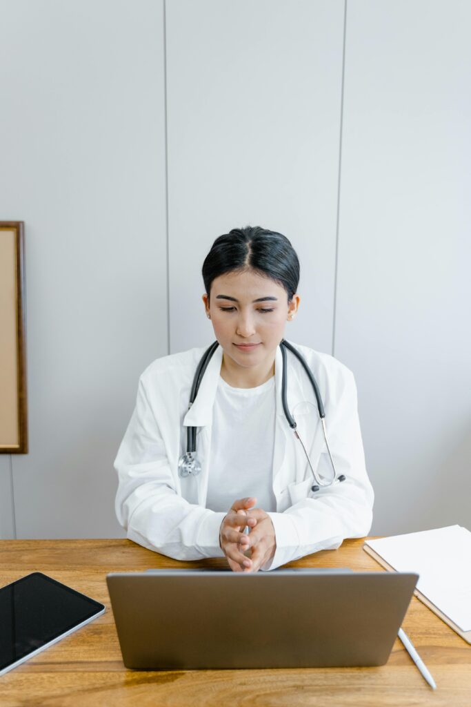 Doctor engaging in online telemedicine consultation via laptop indoors.